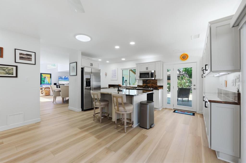 A modern kitchen features white cabinetry, a central island with bar stools, and light wood flooring — 2510 NIGHTINGALE LANE UNIT 54, BRADENTON, FL