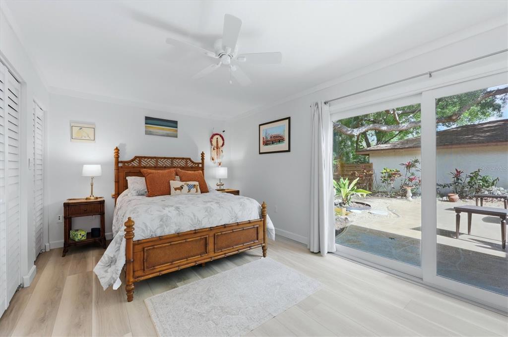 A bedroom features a bamboo bed, light wood flooring, and sliding glass doors to a patio — 2510 NIGHTINGALE LANE UNIT 54, BRADENTON, FL