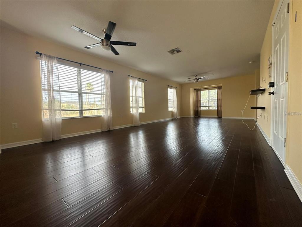 A spacious living room features dark hardwood floors, multiple windows, and two ceiling fans — 4405 TUSCAN LOON DRIVE, TAMPA, FL