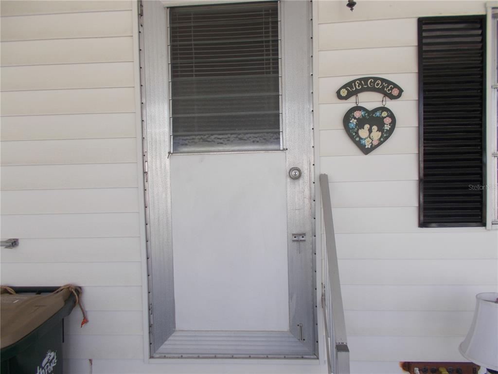 A white storm door with a window is mounted on the exterior siding of a home — 5039 PALENA BOULEVARD, NORTH PORT, FL