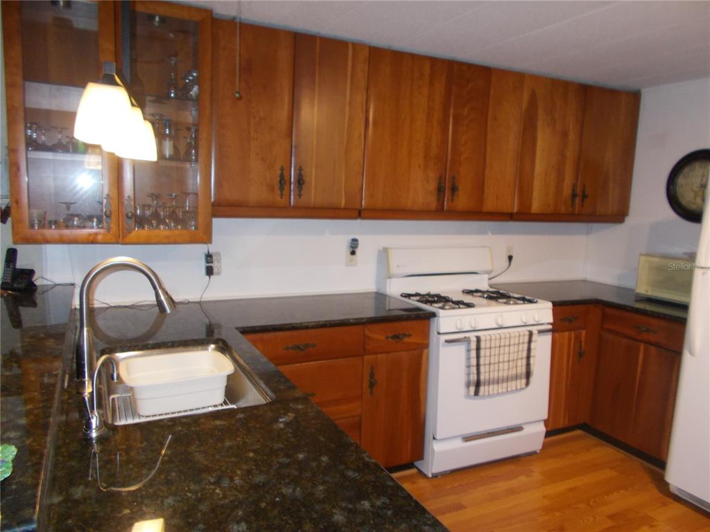 A kitchen features wood cabinets, dark granite countertops, a white stove, and a sink — 5039 PALENA BOULEVARD, NORTH PORT, FL