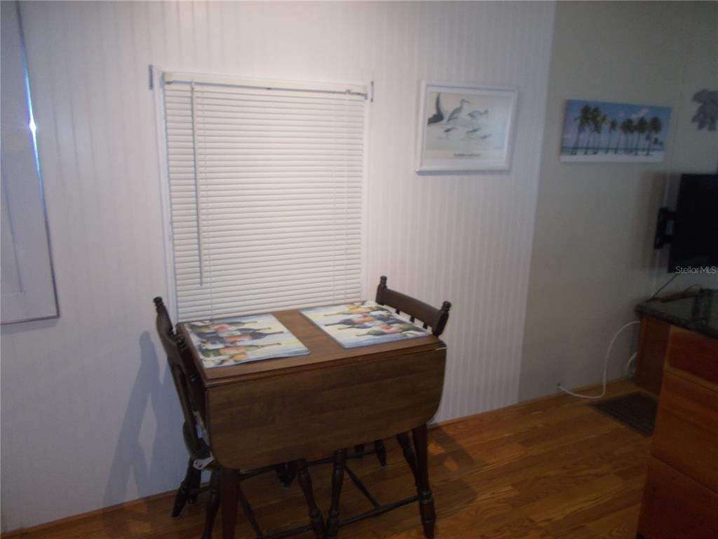 A small wooden drop-leaf table with two chairs sits in a room with wood flooring — 5039 PALENA BOULEVARD, NORTH PORT, FL
