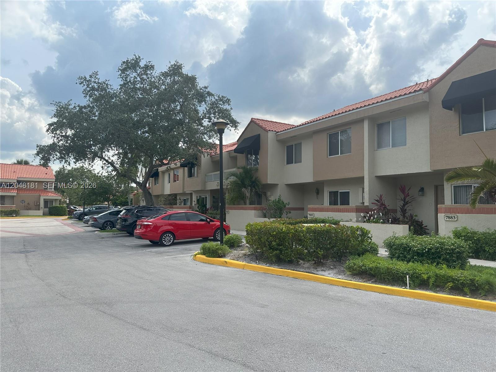 A red sedan is parked in front of a two-story townhouse complex with tiled roofs — 7885 NW 7th Ct # 406, Plantation FL 33324, PLANTATION, FL