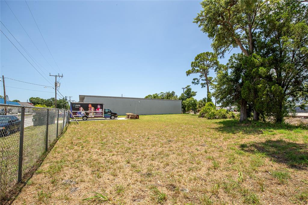 A vacant, grassy lot sits next to a commercial building and a parked moving truck — 2169 10TH STREET, SARASOTA, FL