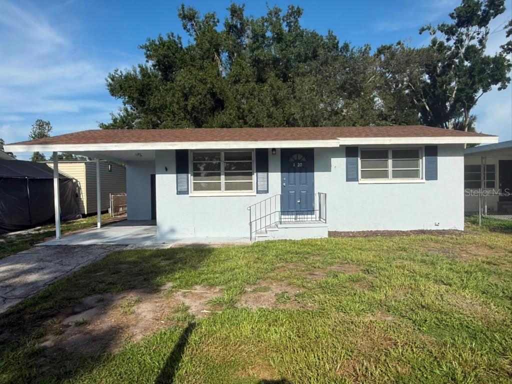 A light blue single-story house features a brown roof, a carport, and a front entrance — 1220 12TH AVENUE W, PALMETTO, FL