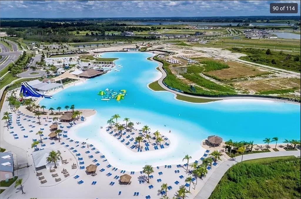 An aerial view of a large turquoise swimming lagoon with sandy beaches and water slides — 8379 ENDER HILLS DRIVE, WESLEY CHAPEL, FL