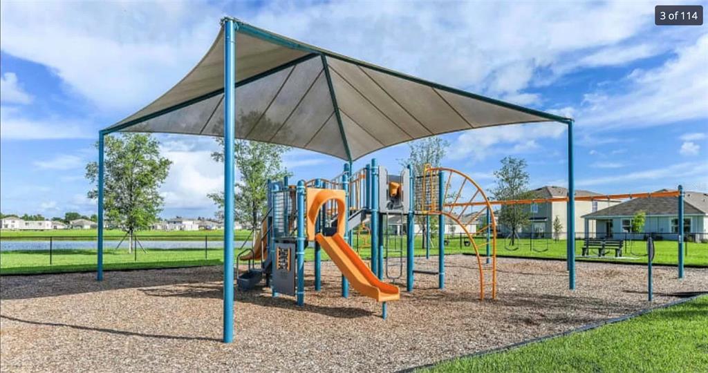 A playground with a large shade canopy, slides, and climbing structures sits on wood chips — 8379 ENDER HILLS DRIVE, WESLEY CHAPEL, FL