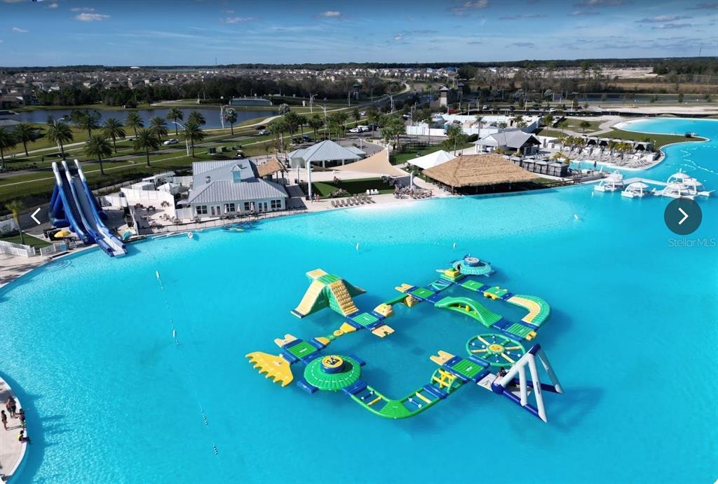 An aerial view of a large turquoise swimming lagoon with an inflatable obstacle course — 8379 ENDER HILLS DRIVE, WESLEY CHAPEL, FL