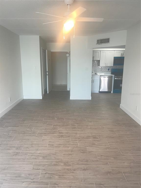 A view of an open-concept living area with wood-look tile flooring and a kitchen — 10365 PARADISE BOULEVARD UNIT 27, ST PETERSBURG, FL