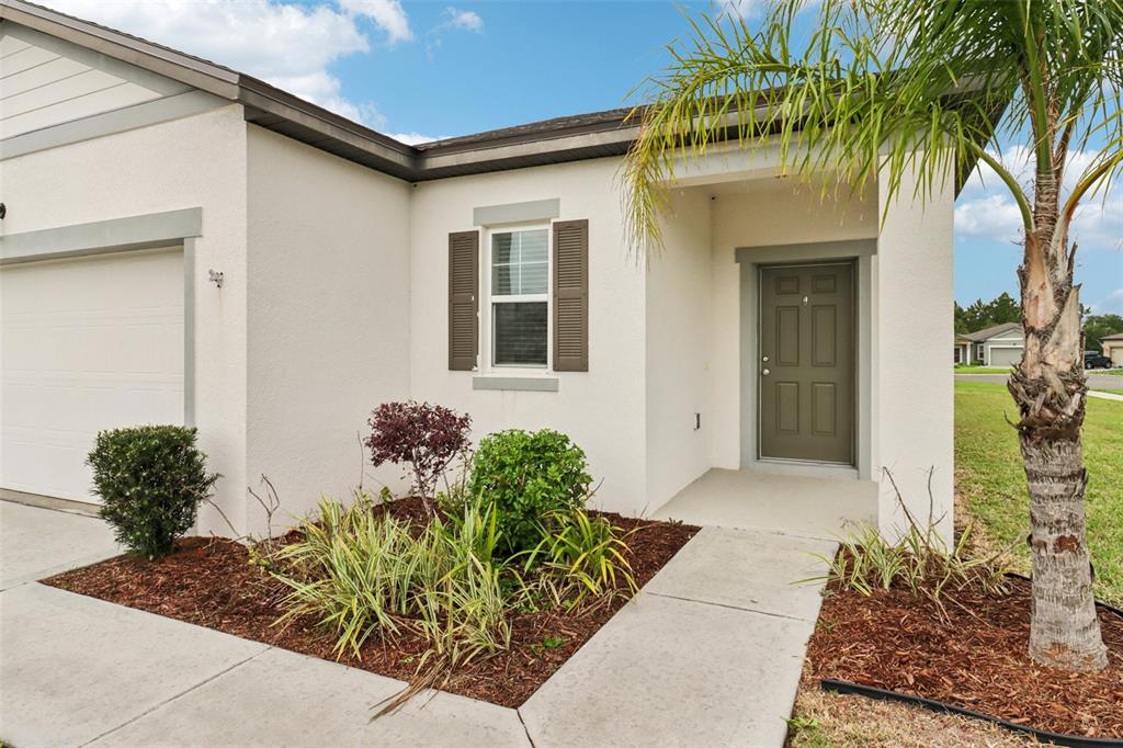 The exterior of a single-story home features a garage, a front door, and landscaping — 3098 NEVERLAND DRIVE, NEW SMYRNA BEACH, FL