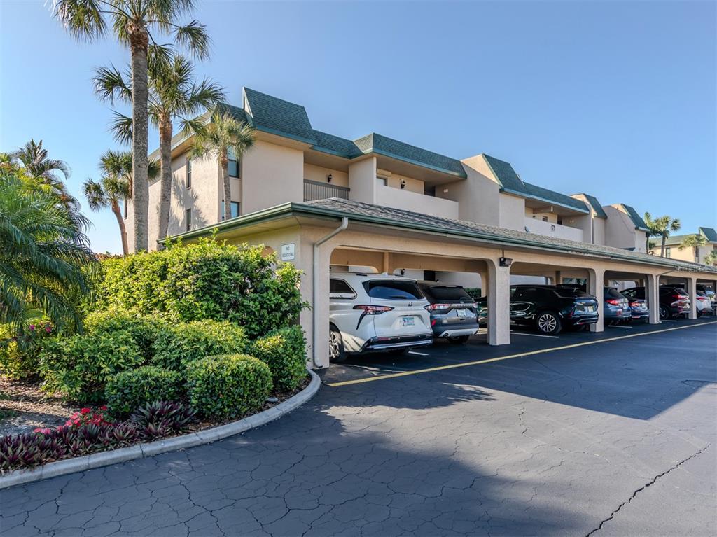 A multi-story apartment building with a covered parking area and palm trees — 601 SHREVE STREET UNIT 51B, PUNTA GORDA, FL