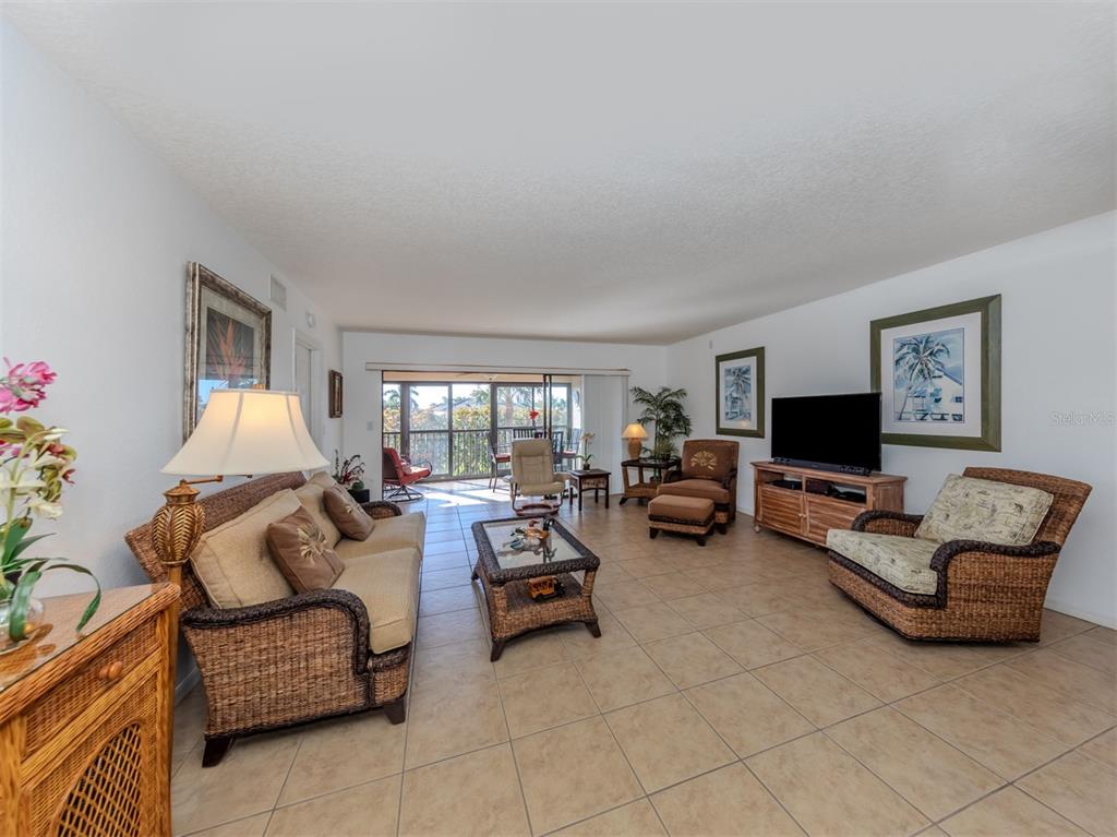 A living room features wicker furniture, tile flooring, and a sliding door to a balcony — 601 SHREVE STREET UNIT 51B, PUNTA GORDA, FL