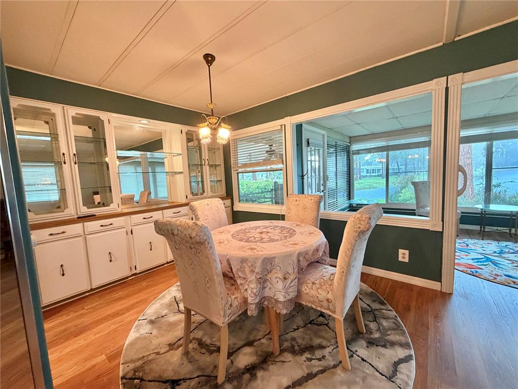 A dining area features a round table, four chairs, a built-in hutch, and wood flooring — 320 PALO VERDE DRIVE, LEESBURG, FL