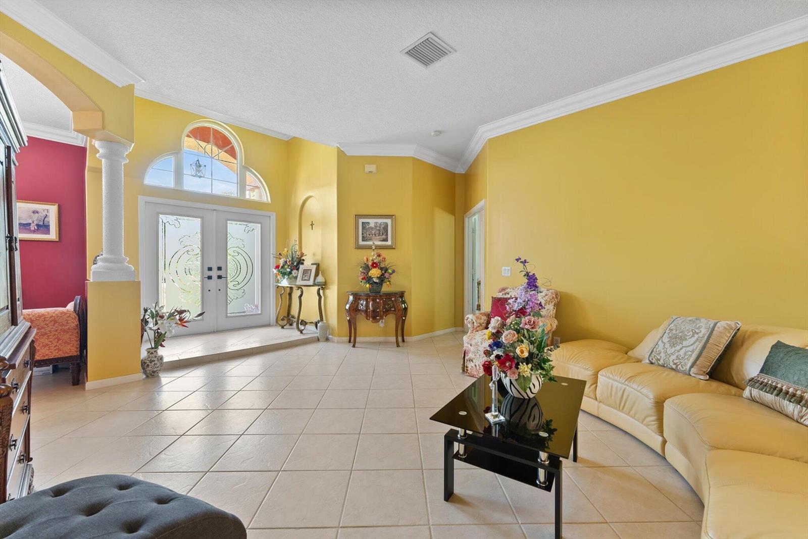 A spacious living room features yellow walls, tile flooring, a glass coffee table, and entryway — 14844 Tangerine Boulevard, FL 33470, FL