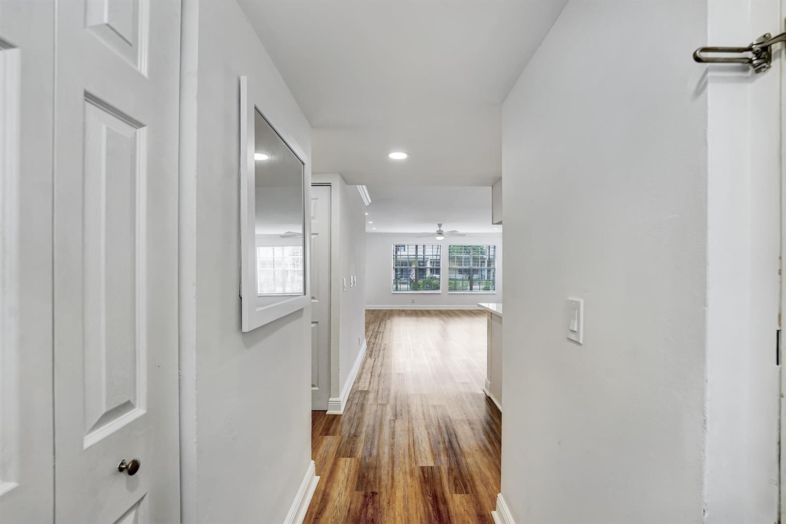 A hallway with light-colored walls and wood-look flooring leads into an open living area — 6315 La Costa Drive # A, Boca Raton FL 33433, BOCA RATON, FL