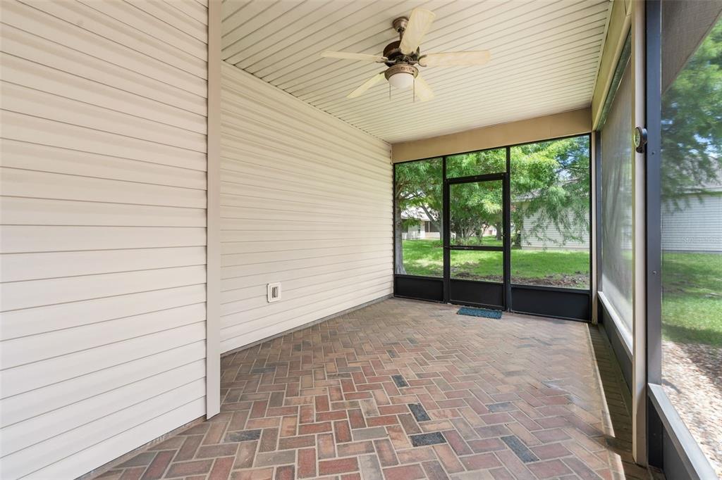 A screened-in porch features a herringbone brick floor, light-colored siding, and a ceiling fan — 4912 NW 79TH ROAD, GAINESVILLE, FL