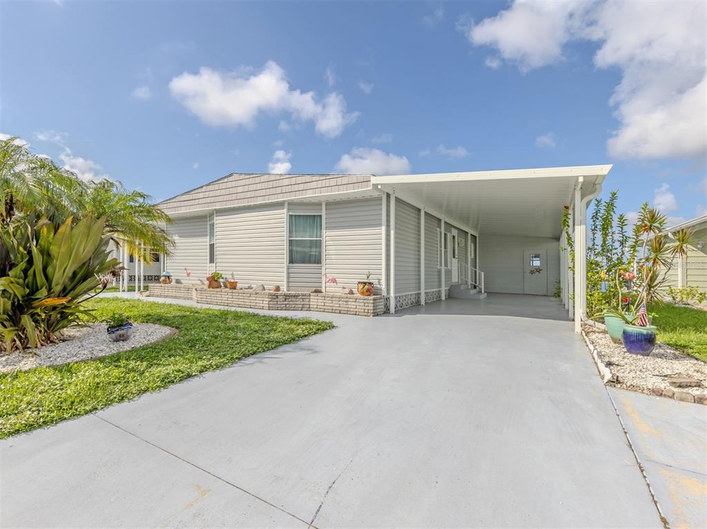 A single-story manufactured home with light gray siding, a carport, and a concrete driveway — 97 LAKEVIEW DRIVE, NORTH PORT, FL