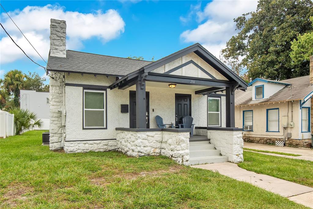A white stucco bungalow with a stone chimney and a covered front porch — 210 BELLEVUE AVENUE, DAYTONA BEACH, FL