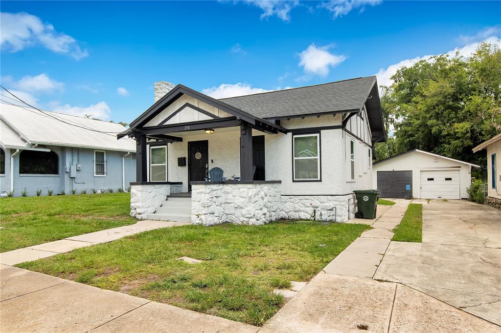A white stucco bungalow with a stone base, dark trim, and a detached garage — 210 BELLEVUE AVENUE, DAYTONA BEACH, FL