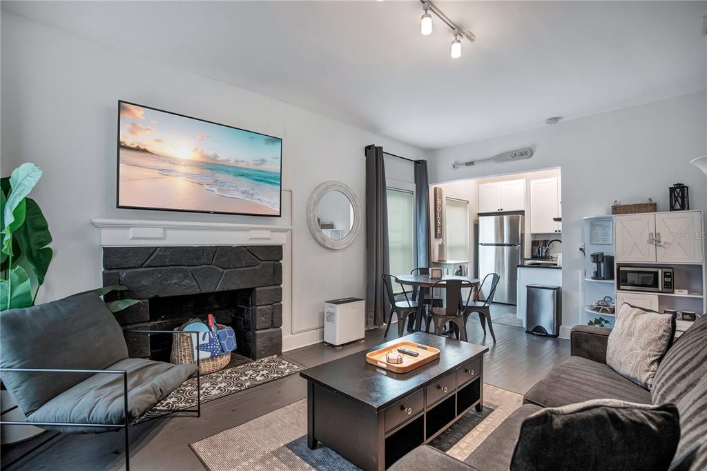 A living room features a stone fireplace, a wall-mounted television, and an adjacent dining area — 210 BELLEVUE AVENUE, DAYTONA BEACH, FL