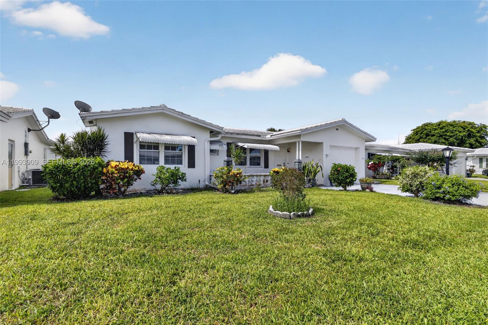 A single-story white house features a front lawn, landscaping, and a small attached garage — 1104 Ocean Ave, Boynton Beach FL 33426, BOYNTON BEACH, FL