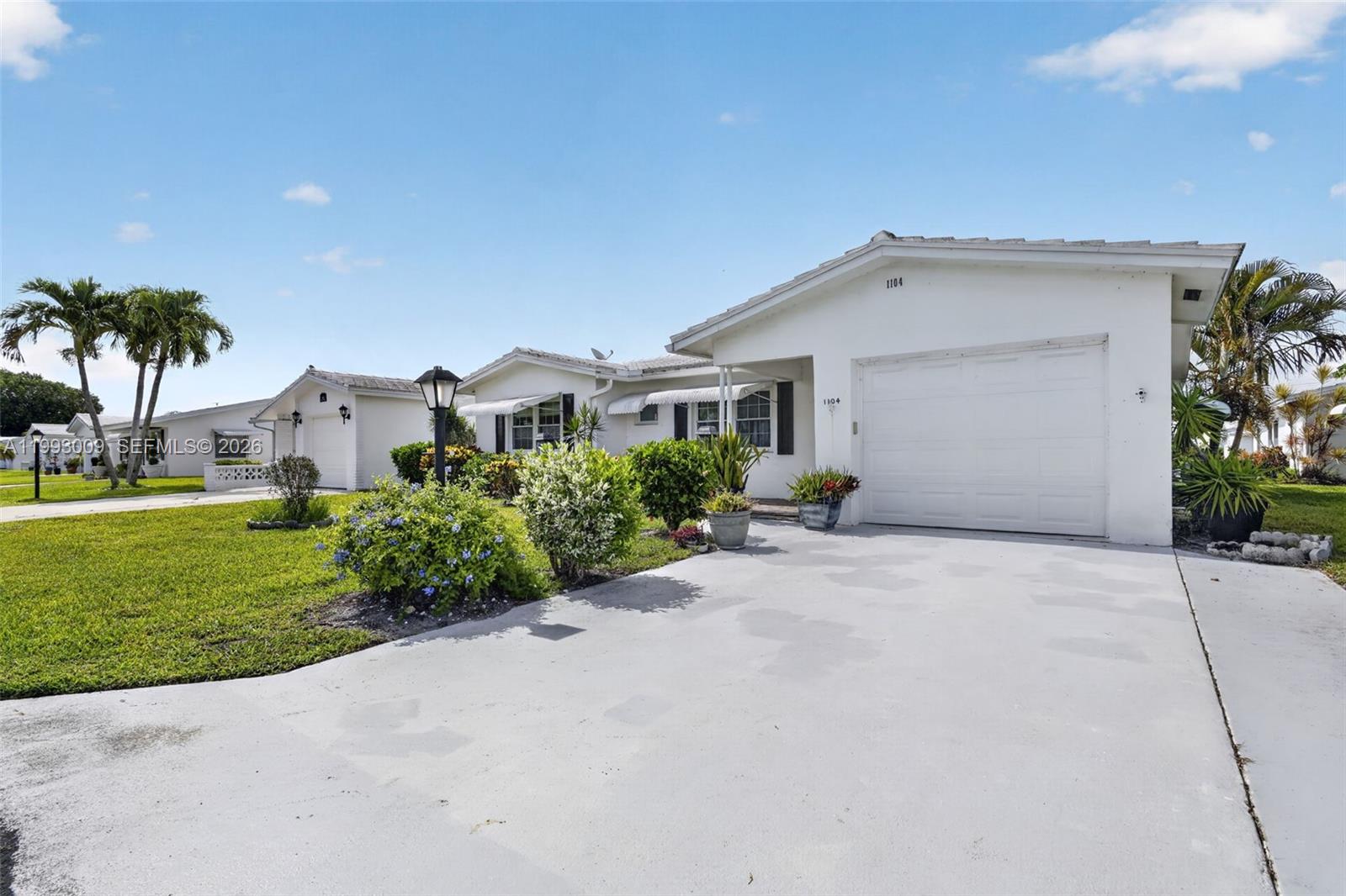 A single-story white house with a garage and a front lawn under a blue sky — 1104 Ocean Ave, Boynton Beach FL 33426, BOYNTON BEACH, FL