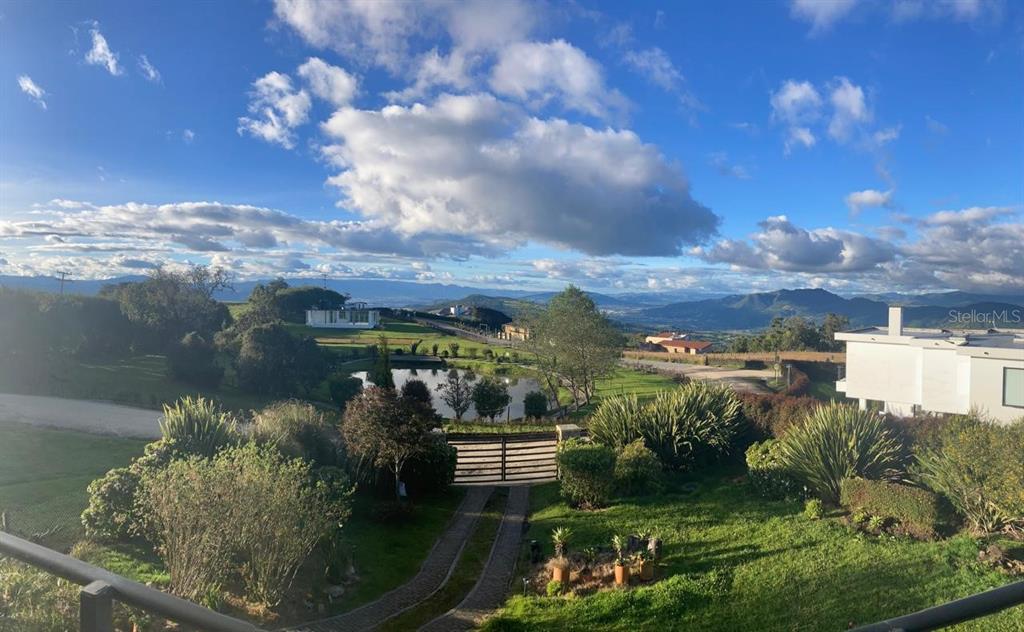 A scenic view of a grassy landscape with a pond, trees, and distant mountains — 16 VEREDA YERBABUENA, VILLAS DE YERBABUENA, FL