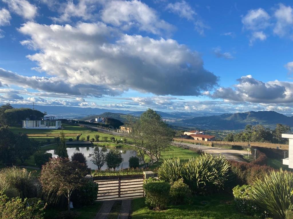 A scenic view of a pond, green landscape, and distant mountains under a cloudy sky — 16 VEREDA YERBABUENA, VILLAS DE YERBABUENA, FL