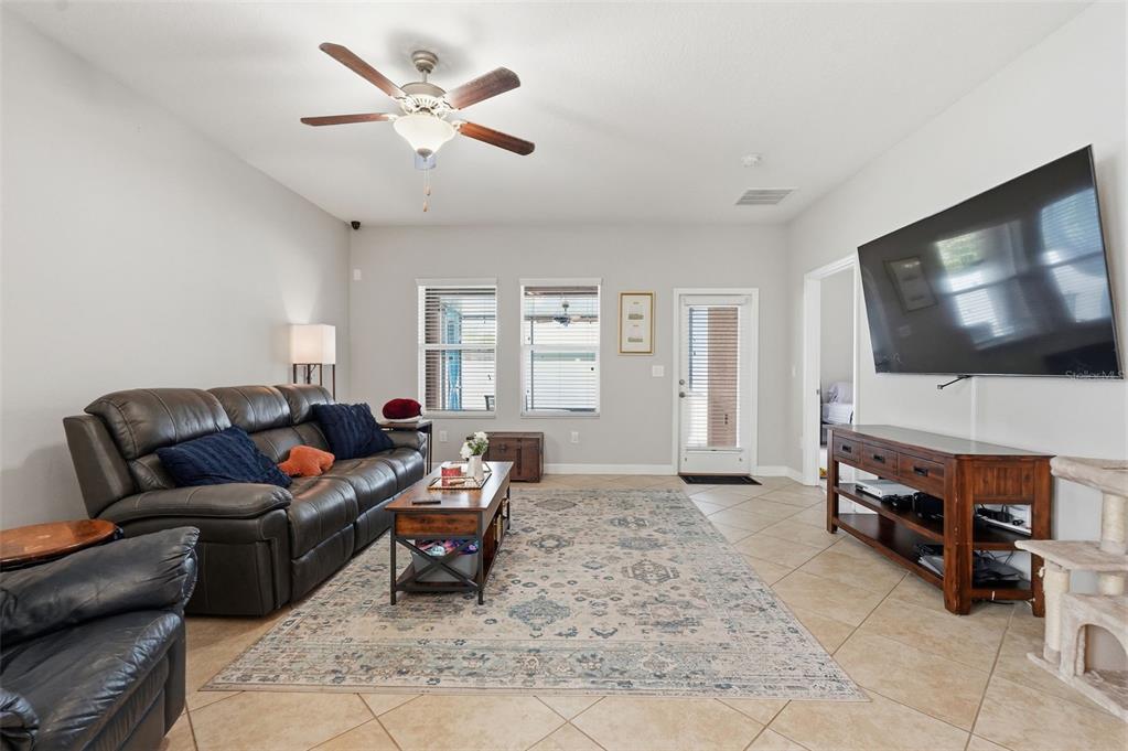 A living room features a leather sofa, a coffee table, a rug, and a wall-mounted television — 11804 VALHALLA WOODS DRIVE, RIVERVIEW, FL
