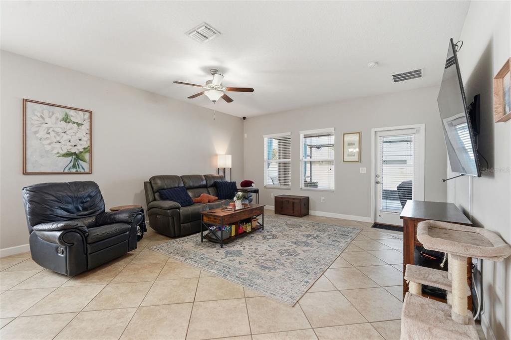 A living room features tile flooring, a leather sofa and recliner, and a wall-mounted television — 11804 VALHALLA WOODS DRIVE, RIVERVIEW, FL