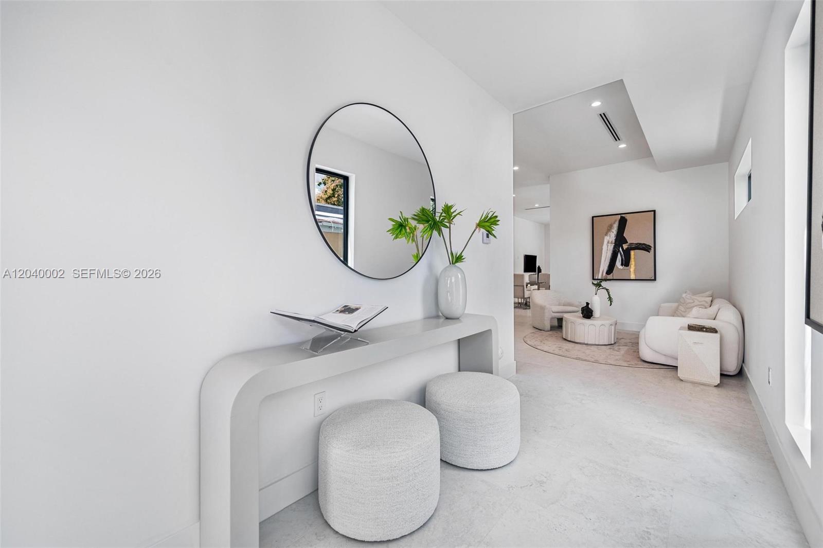 A minimalist entryway features a console table, two ottomans, and a round wall mirror — 2939 SW 21st st, Miami FL 33145, MIAMI, FL