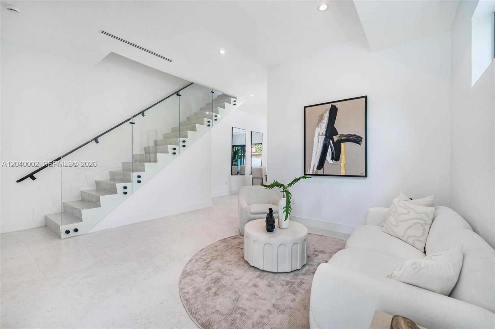 A modern living area features a glass-railed staircase, white walls, and a neutral-toned sofa — 2939 SW 21st st, Miami FL 33145, MIAMI, FL