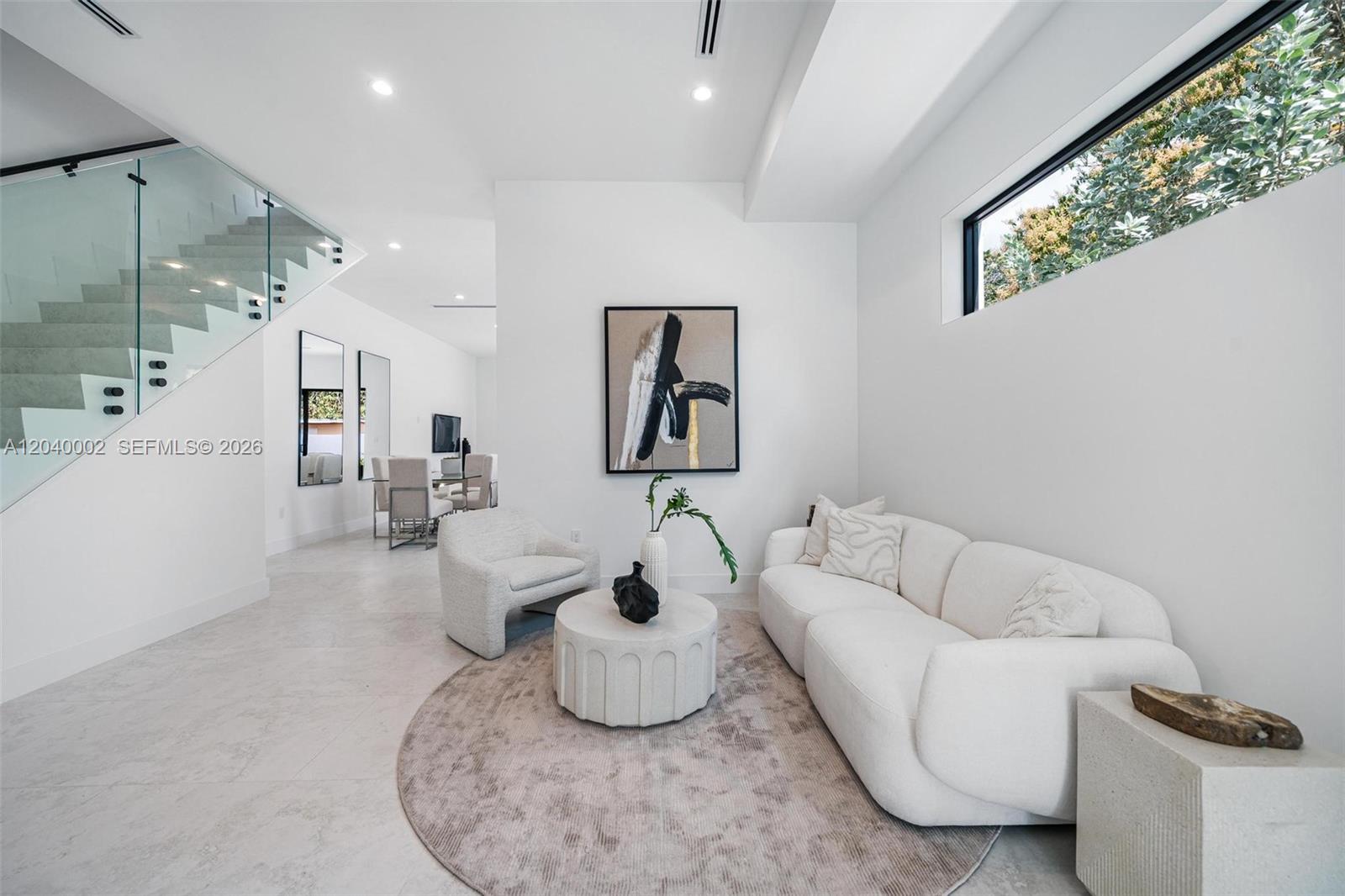 A modern living room features white furniture, a circular rug, and a glass-railed staircase — 2939 SW 21st st, Miami FL 33145, MIAMI, FL