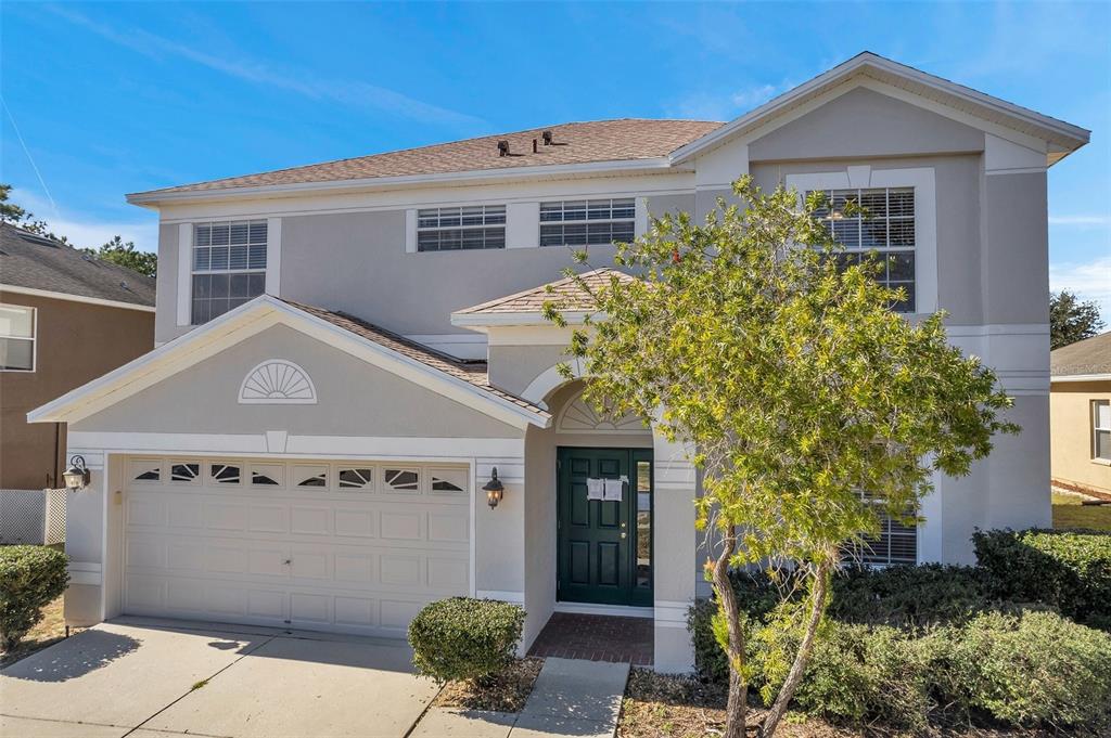 A two-story house with a beige stucco exterior, a two-car garage, and a green door — 4069 BRAEMERE DRIVE, SPRING HILL, FL