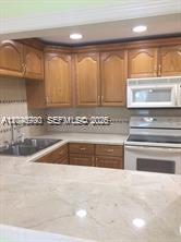 A kitchen features light wood cabinets, a beige countertop, and a white microwave above the stove — 9301 SW 92nd Ave # A211, Miami FL 33176, MIAMI, FL
