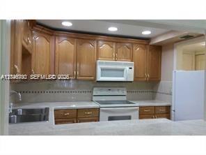 A kitchen features wood cabinets, white appliances, and a light-colored countertop — 9301 SW 92nd Ave # A211, Miami FL 33176, MIAMI, FL