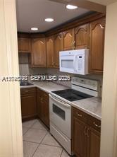 A kitchen features wood cabinets, a white microwave, a white stove, and light tile flooring — 9301 SW 92nd Ave # A211, Miami FL 33176, MIAMI, FL