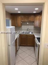 A galley kitchen features wood cabinets, light countertops, and tiled flooring — 9301 SW 92nd Ave # A211, Miami FL 33176, MIAMI, FL