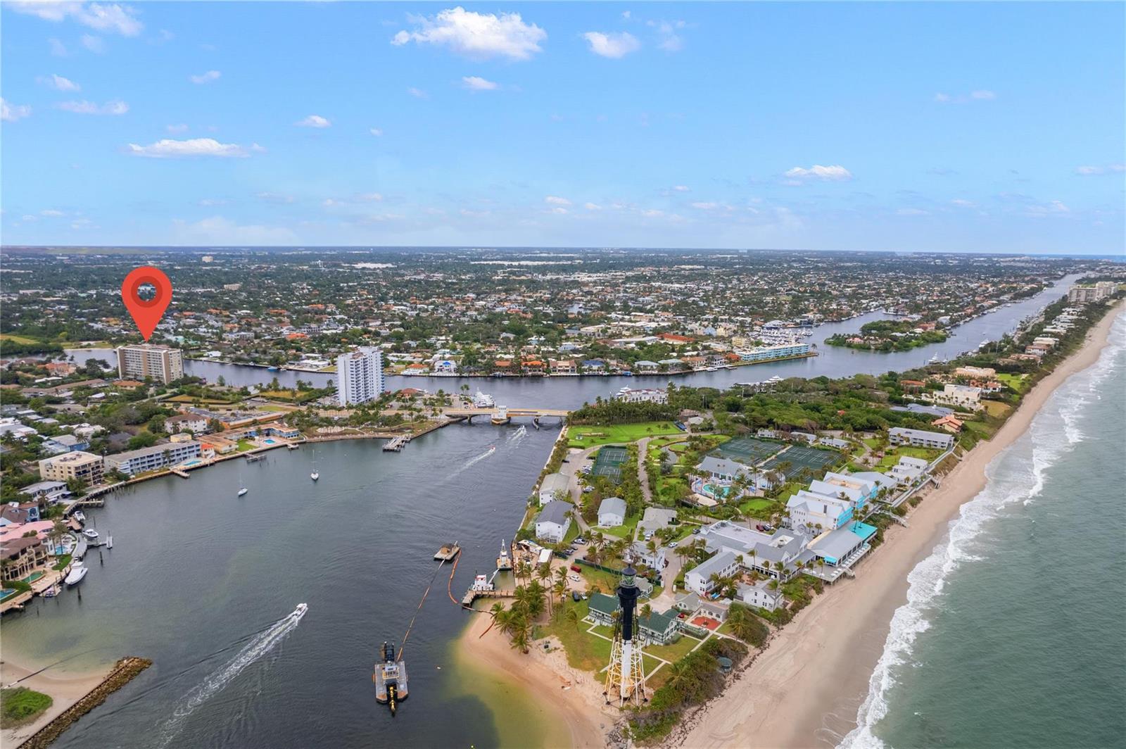 An aerial view shows a lighthouse, a coastal inlet, and residential buildings near the beach — 2611 N Riverside Drive # 307, Pompano Beach FL 33062, POMPANO BEACH, FL