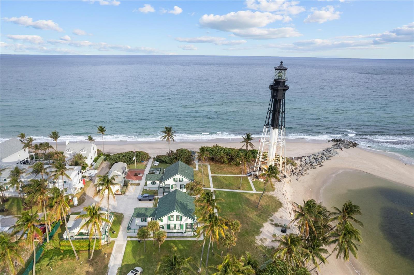 An aerial view shows a lighthouse, several buildings, and palm trees along a sandy beach — 2611 N Riverside Drive # 307, Pompano Beach FL 33062, POMPANO BEACH, FL
