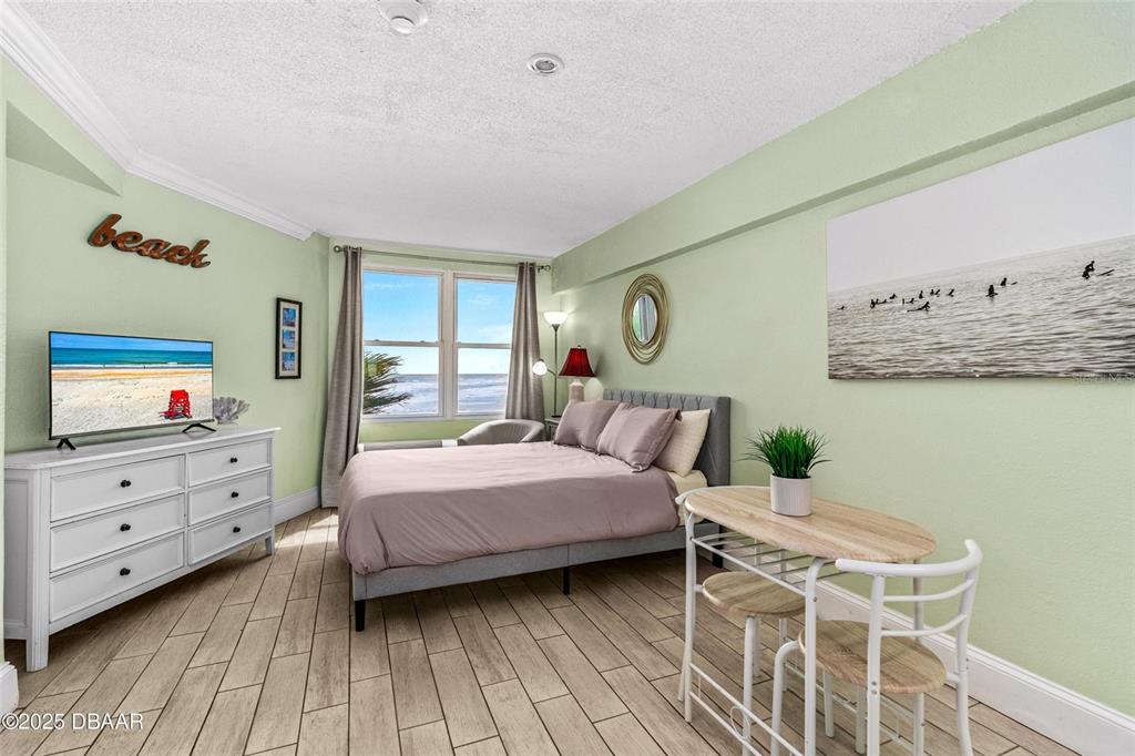 A bedroom features a bed, a dresser with a television, and a small dining set — 2301 S ATLANTIC AVENUE UNIT 501, DAYTONA BEACH, FL
