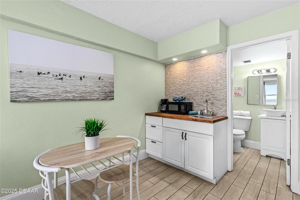A small kitchenette with white cabinets and a wood countertop sits beside a dining area — 2301 S ATLANTIC AVENUE UNIT 501, DAYTONA BEACH, FL
