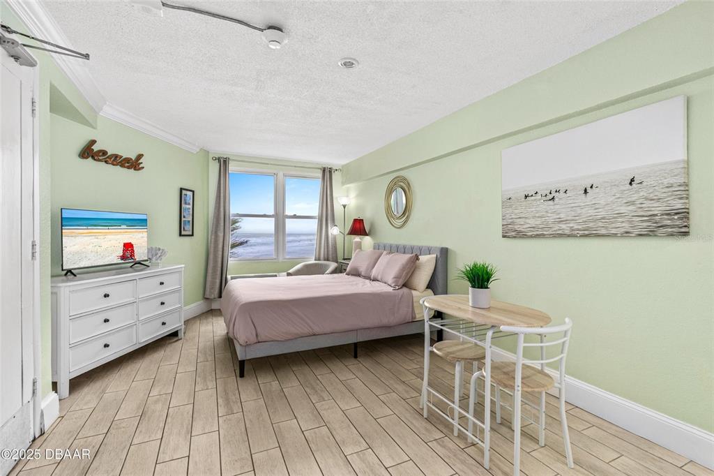 A bedroom features a bed, a dresser with a television, and a small dining set — 2301 S ATLANTIC AVENUE UNIT 501, DAYTONA BEACH, FL