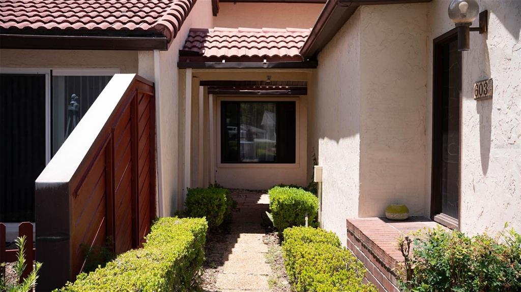 A walkway leads to a recessed entrance with a window and a house number sign — 603 WATERWOOD DRIVE, YALAHA, FL