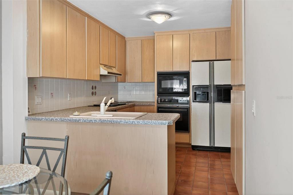 A kitchen features light wood cabinets, a peninsula with a sink, and a white refrigerator — 603 WATERWOOD DRIVE, YALAHA, FL