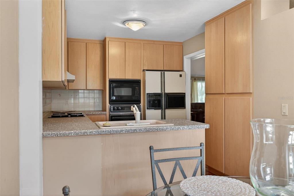 A kitchen features light wood cabinets, a speckled countertop, and a built-in wall oven — 603 WATERWOOD DRIVE, YALAHA, FL