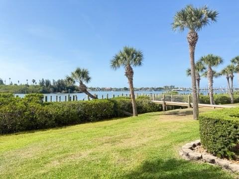 A grassy lawn leads to a wooden dock extending into a bay with palm trees — 460 BOUCHELLE DRIVE UNIT 104, NEW SMYRNA BEACH, FL