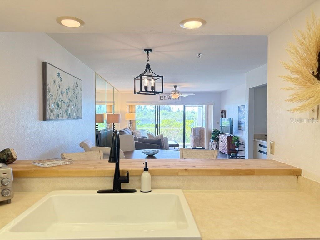 A kitchen sink overlooks a dining area and living room with a view of greenery — 460 BOUCHELLE DRIVE UNIT 104, NEW SMYRNA BEACH, FL
