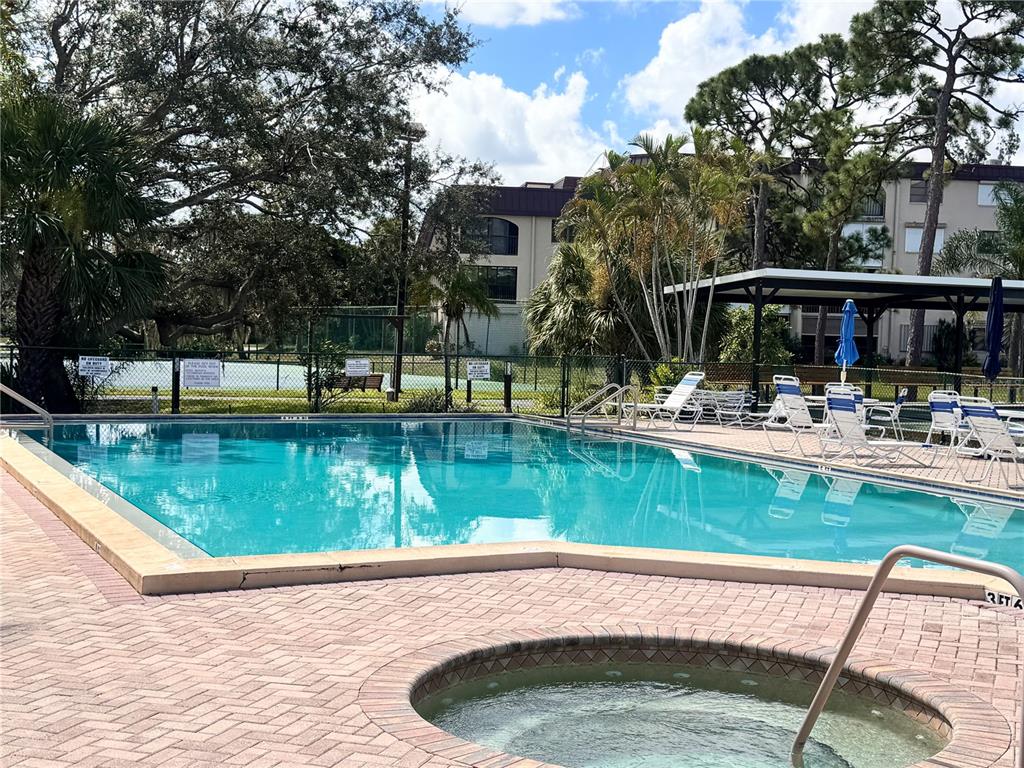 An outdoor swimming pool and a circular hot tub are set on a brick patio — 23465 HARBORVIEW ROAD UNIT 824, PUNTA GORDA, FL