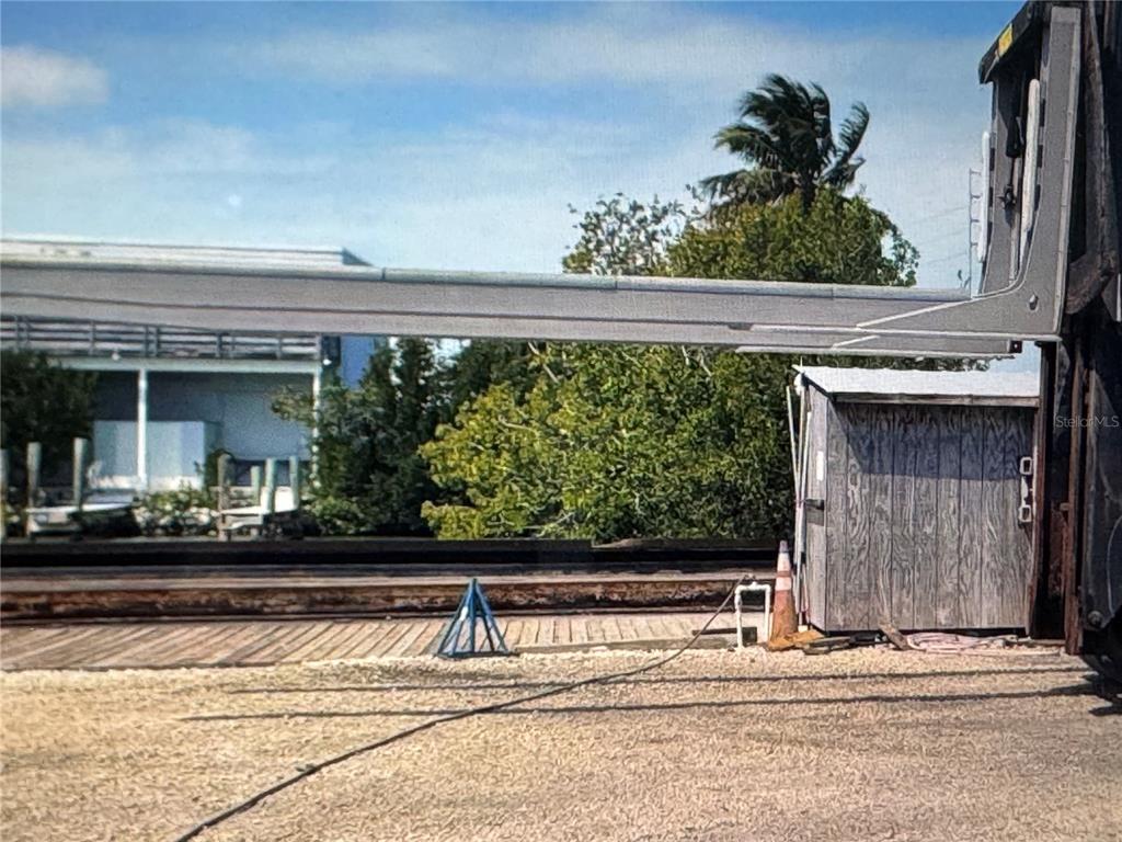 A metal beam extends over a gravel area next to a small wooden shed — 13900 OVERSEAS HWY, MARATHON, FL